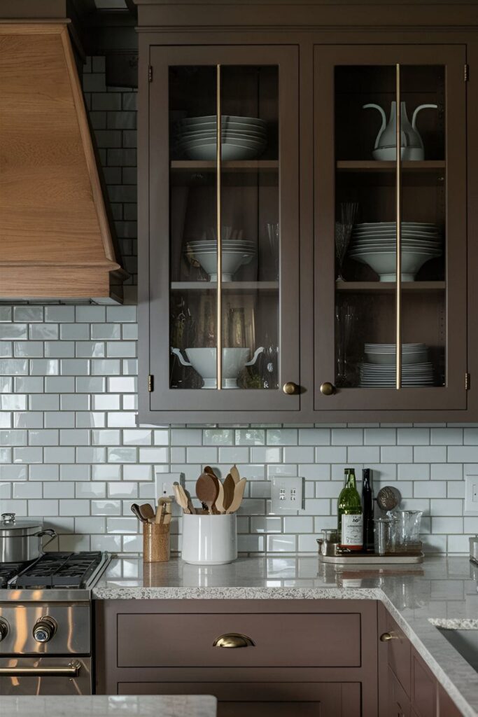 A kitchen with brown cabinets featuring glass doors, showcasing stylish dishes and glassware, adding depth and an open feel