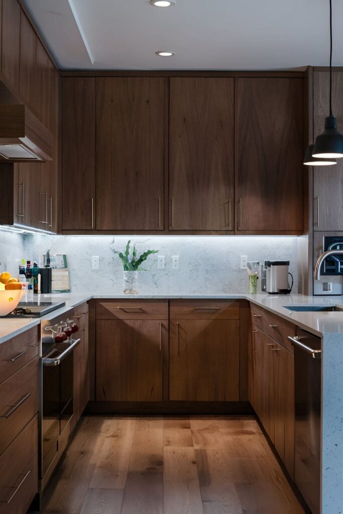 Cherry wood kitchen cabinets with under-cabinet LED lighting illuminating the countertops and enhancing the wood's color