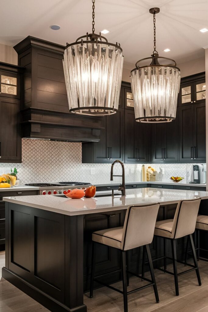 Kitchen with dark cabinets and large, statement light fixtures. Modern chandeliers with glass and metal elements hang over a central island, adding style and light