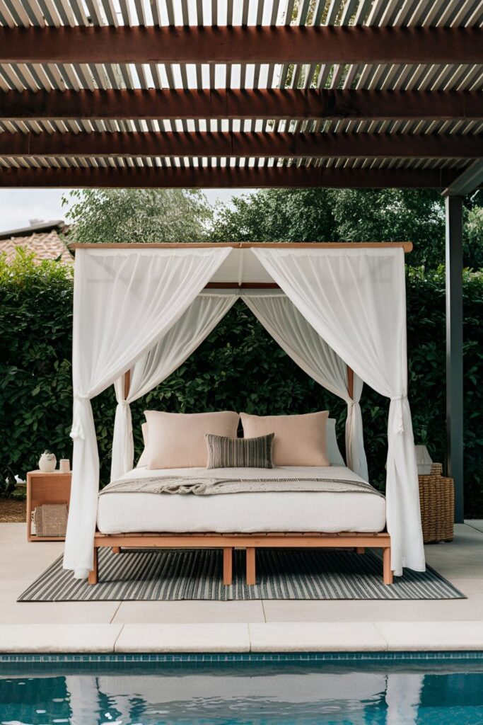 Outdoor canopy bed with weather-resistant fabrics and cushions placed under a pergola near a pool