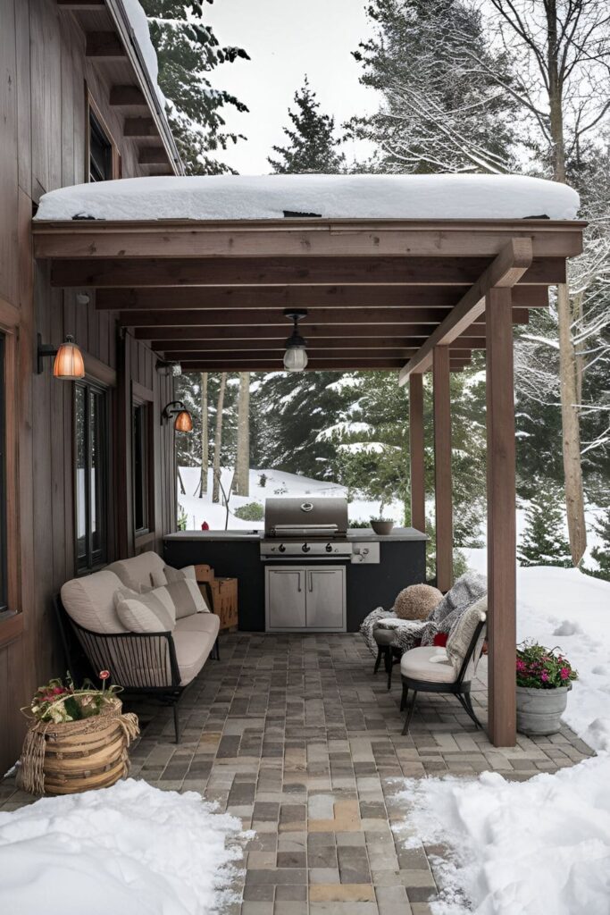 A cozy winter patio with weather-resistant furniture, a sturdy grill, outdoor heaters, cozy blankets, and warm lighting, surrounded by a snowy landscape