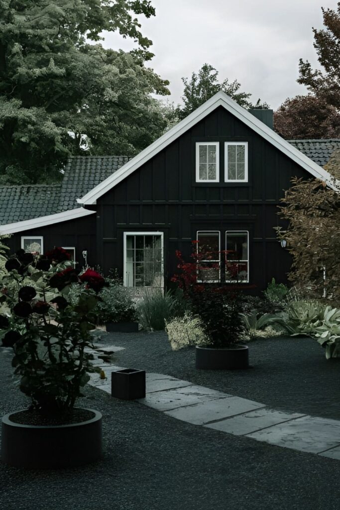 A black house surrounded by monochrome landscaping with dark gravel and plants