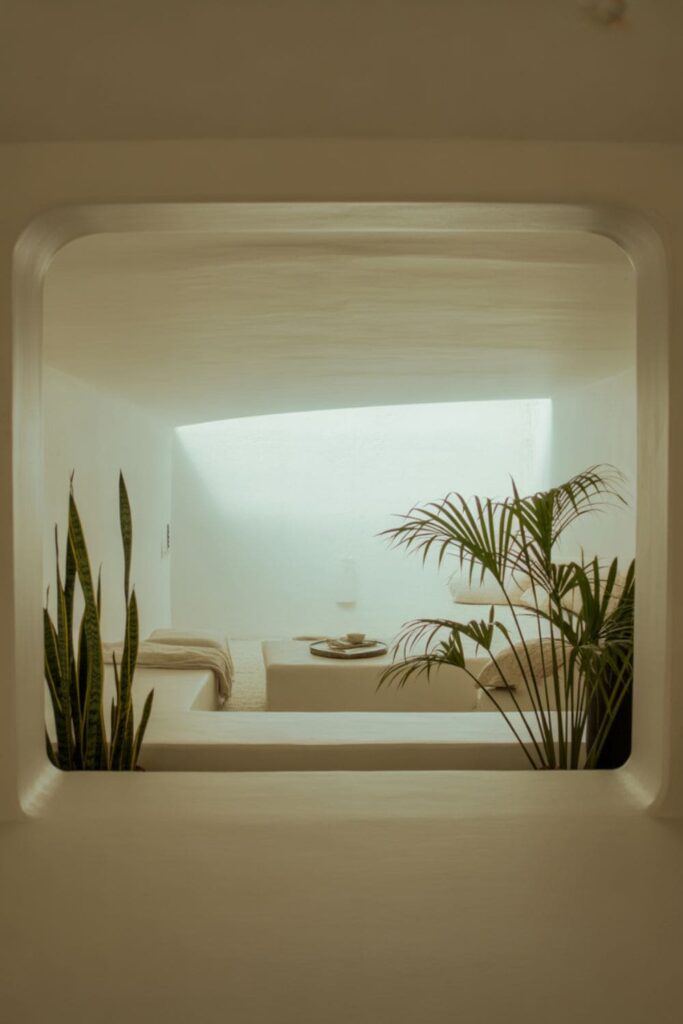 Bright low-ceiling living room with large unobstructed windows, sheer curtains, light furniture, and natural sunlight