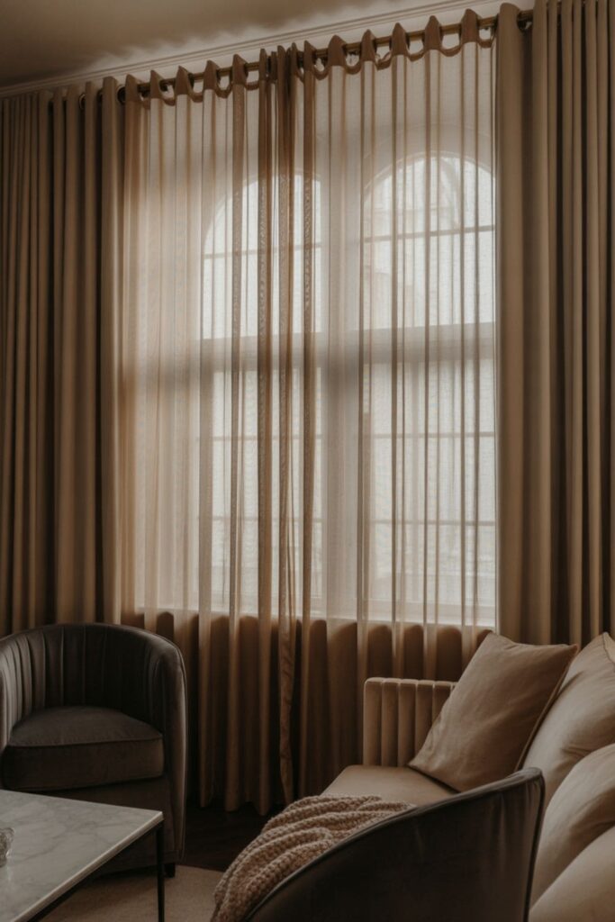 Elegant living room with floor-to-ceiling sheer and heavy layered curtains, luxurious boutique hotel style