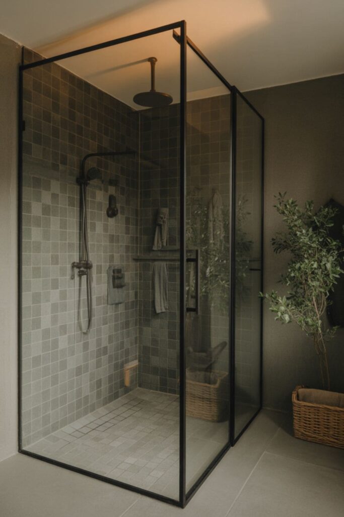 Open modern bathroom with frameless glass shower and dark tiles