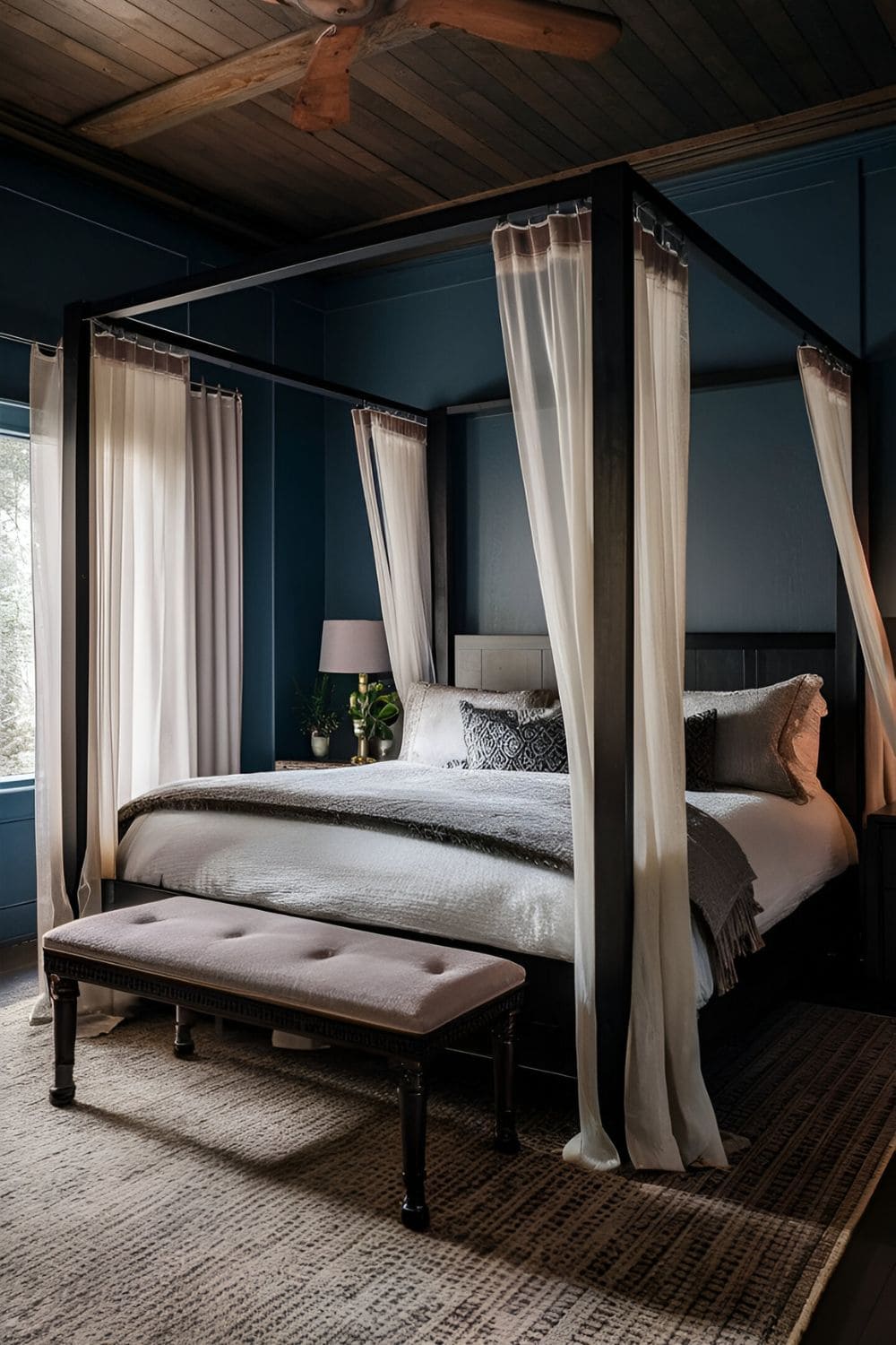 Dramatic dark wood canopy bed with sheer curtains in a romantic and cozy bedroom