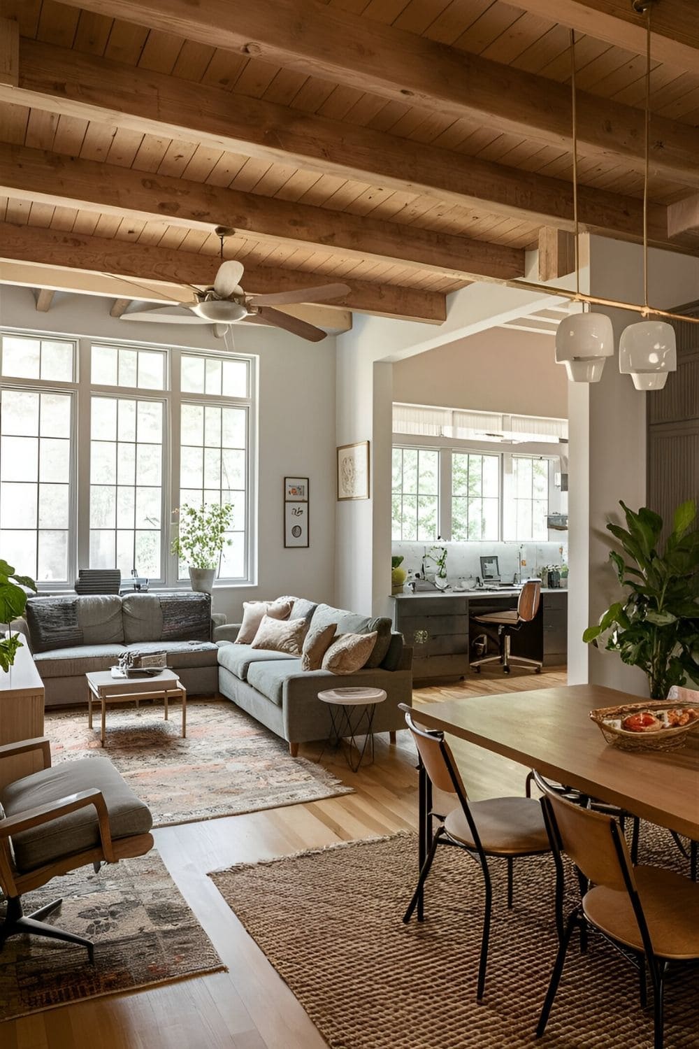 Large living room serving multiple functions including a seating area a workspace and a dining nook defined by rugs and strategically placed furniture to maximize usability