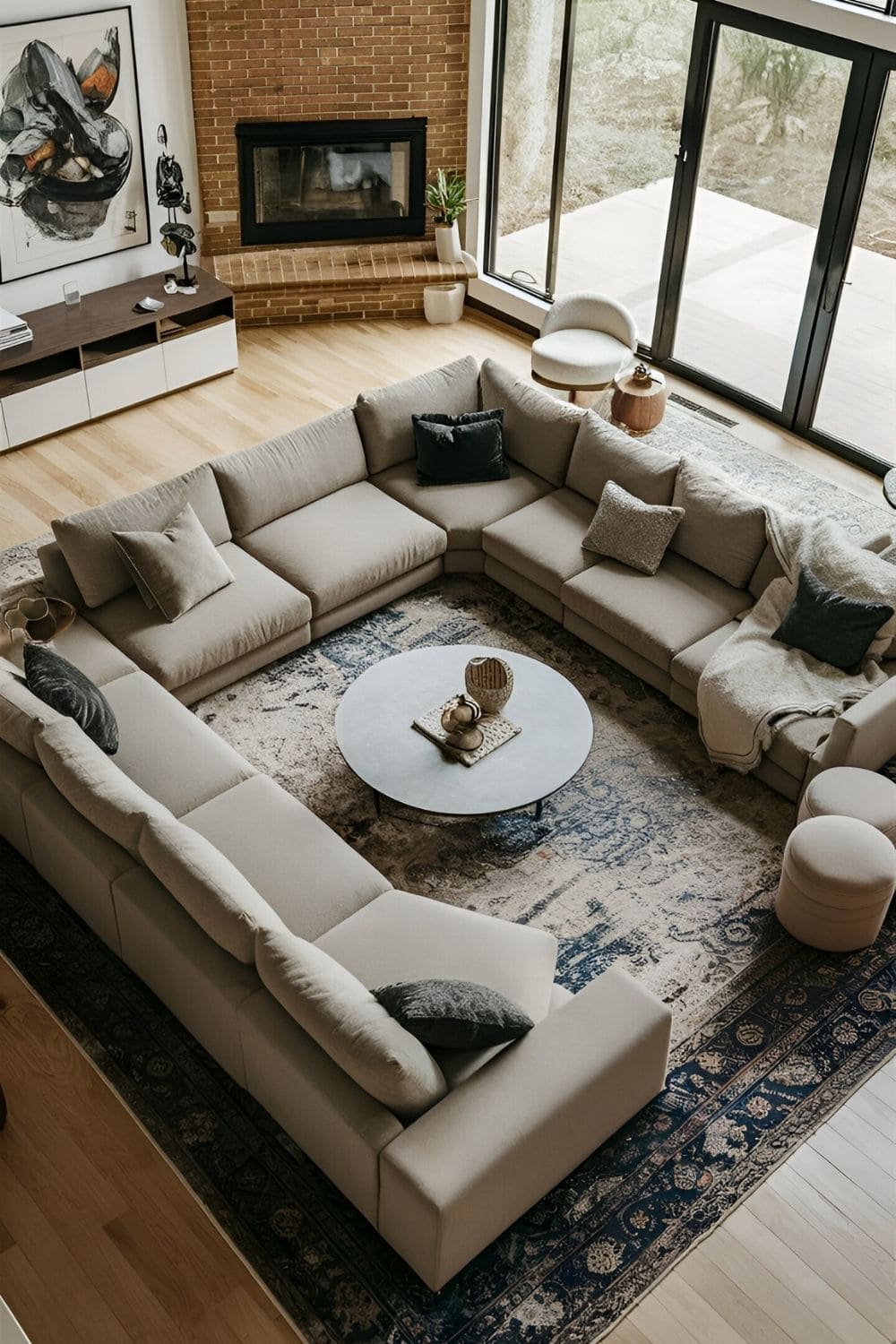 Large living room with a sectional sofa positioned in the center complemented by a large rug and central coffee table creating a cozy and stylish centerpiece