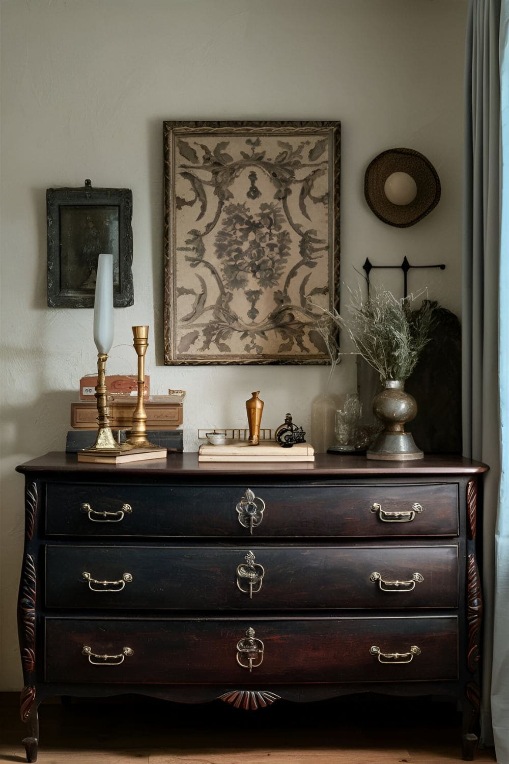 Vintage dark wood dresser with intricate carvings set against a light-colored wall adorned with antique decor items