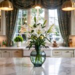 A photograph of a luxurious kitchen centered around a sprawling white marble island.